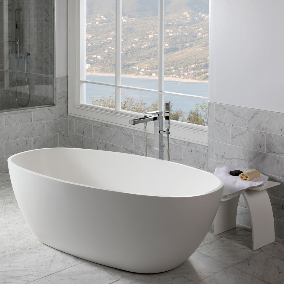 Free-standing soaking bathtub made of white solid surface with an overflow and a decorative solid surface drain; net weight 298 lbs, water capacity 73 gal. W: 63", D:31 1/2", H:21 5/8".